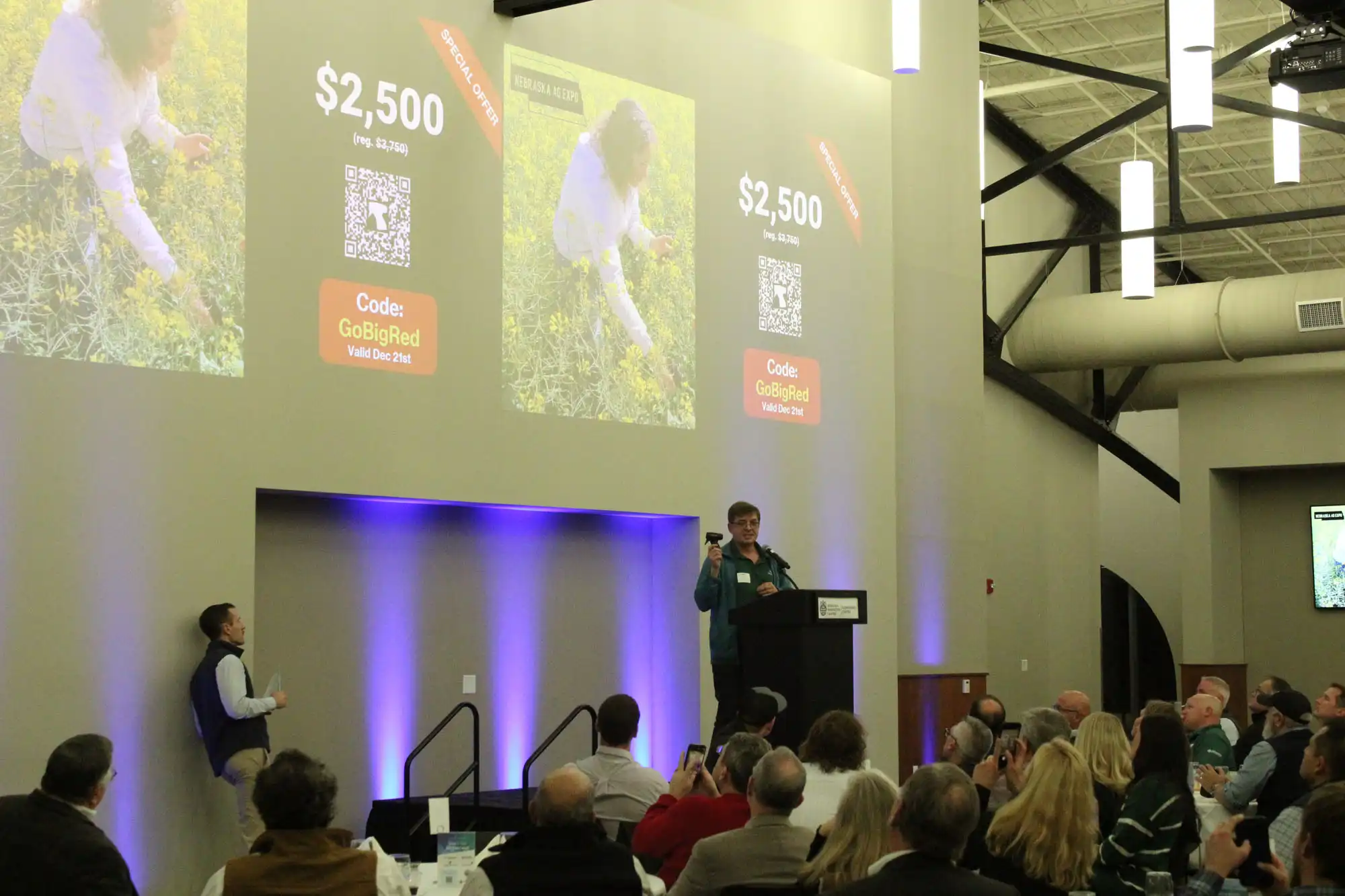 A person speaks at a podium before an audience, at the Nebraska Ag Expo.