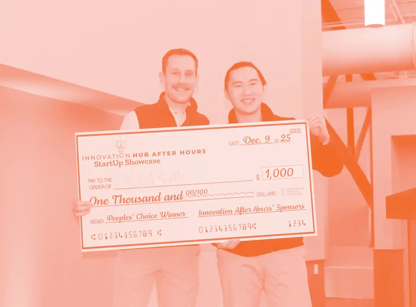 Two men smile and pose with a large cashier's check.