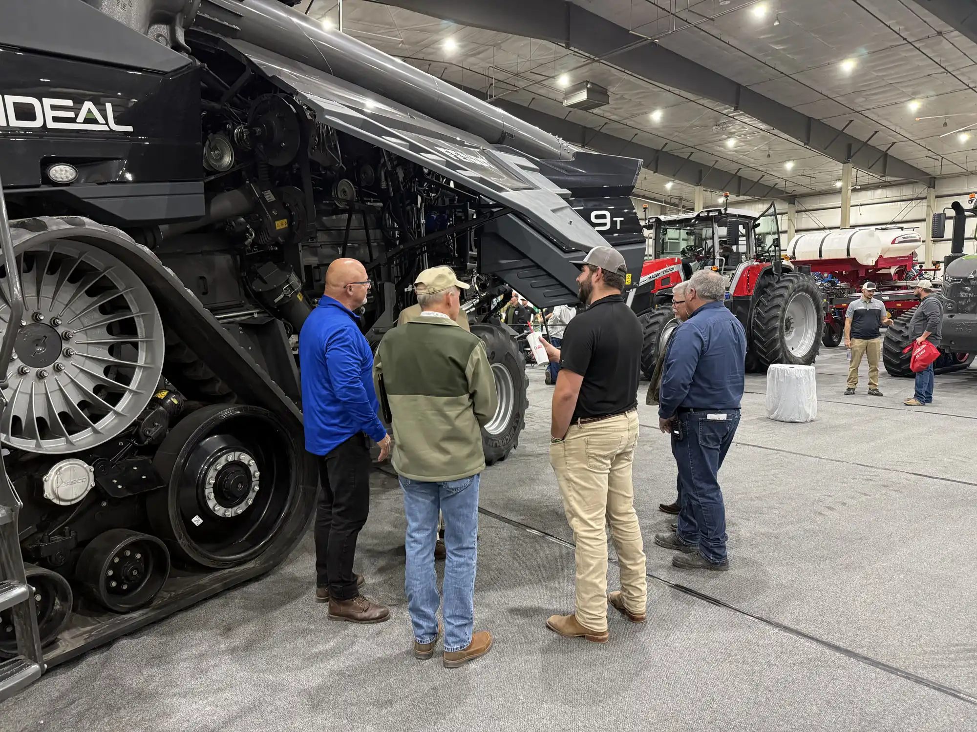 A group of men standing in front of a large tractor discussing something.