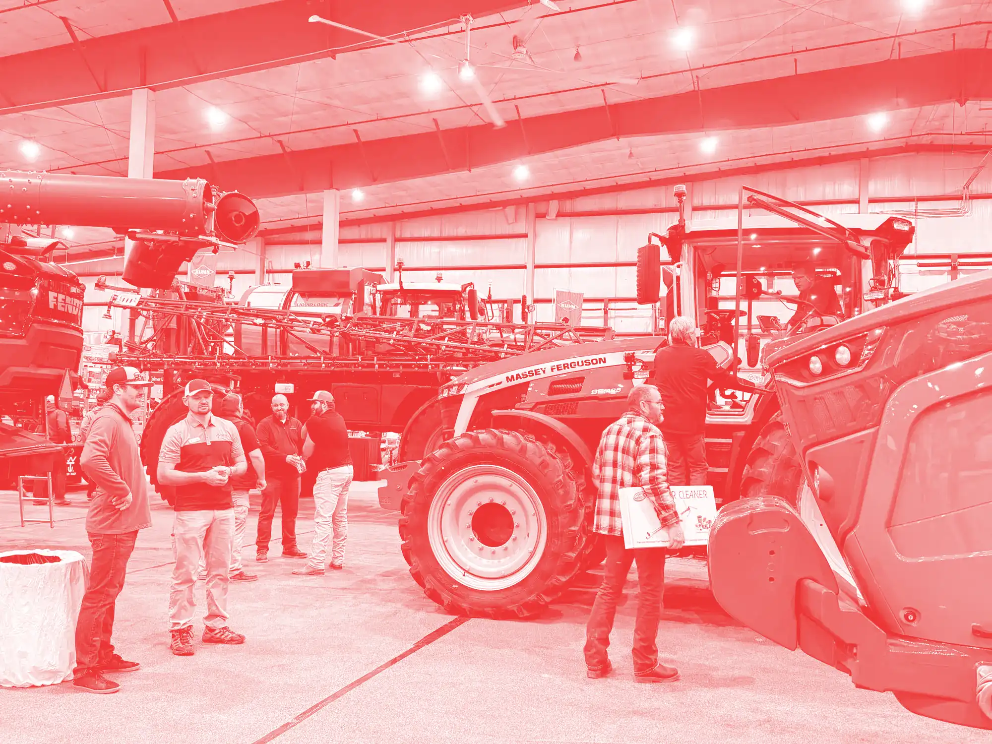 Half a dozen men inspect farm equipment at a large exhibition.